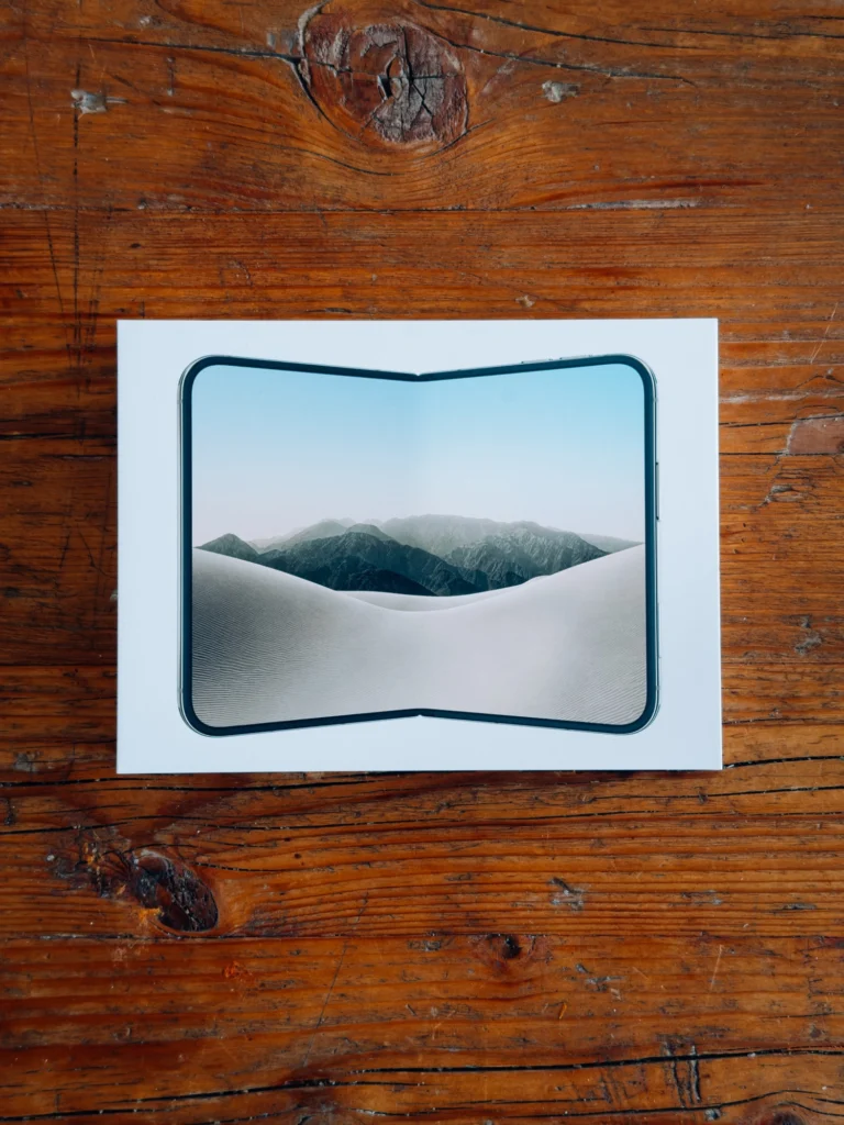 White iPhone Duo box from above on a wooden table, the unfolded Duo printed on the lid